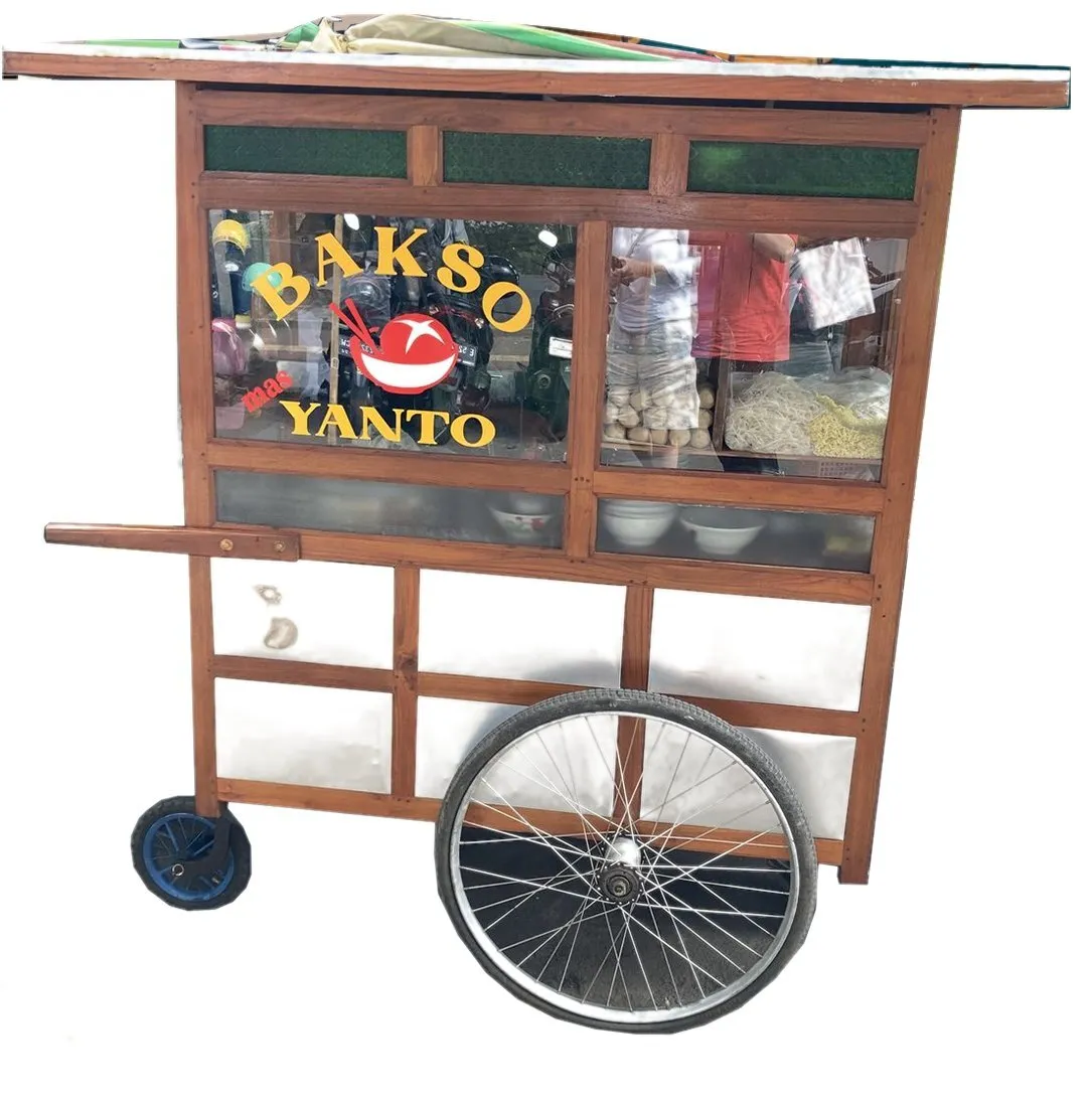 Reference image: a traditional Indonesian gerobak, a wooden street-food cart with glass windows lettered “Bakso Yanto”, a handle and two mismatched wheels.