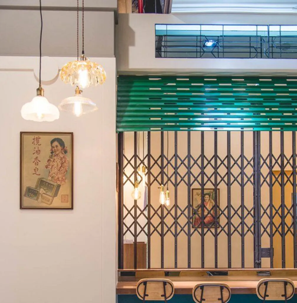 Reference image: a café wall with a vintage Chinese advertisement poster, glass pendants, a green roller shutter and a folding steel grille.
